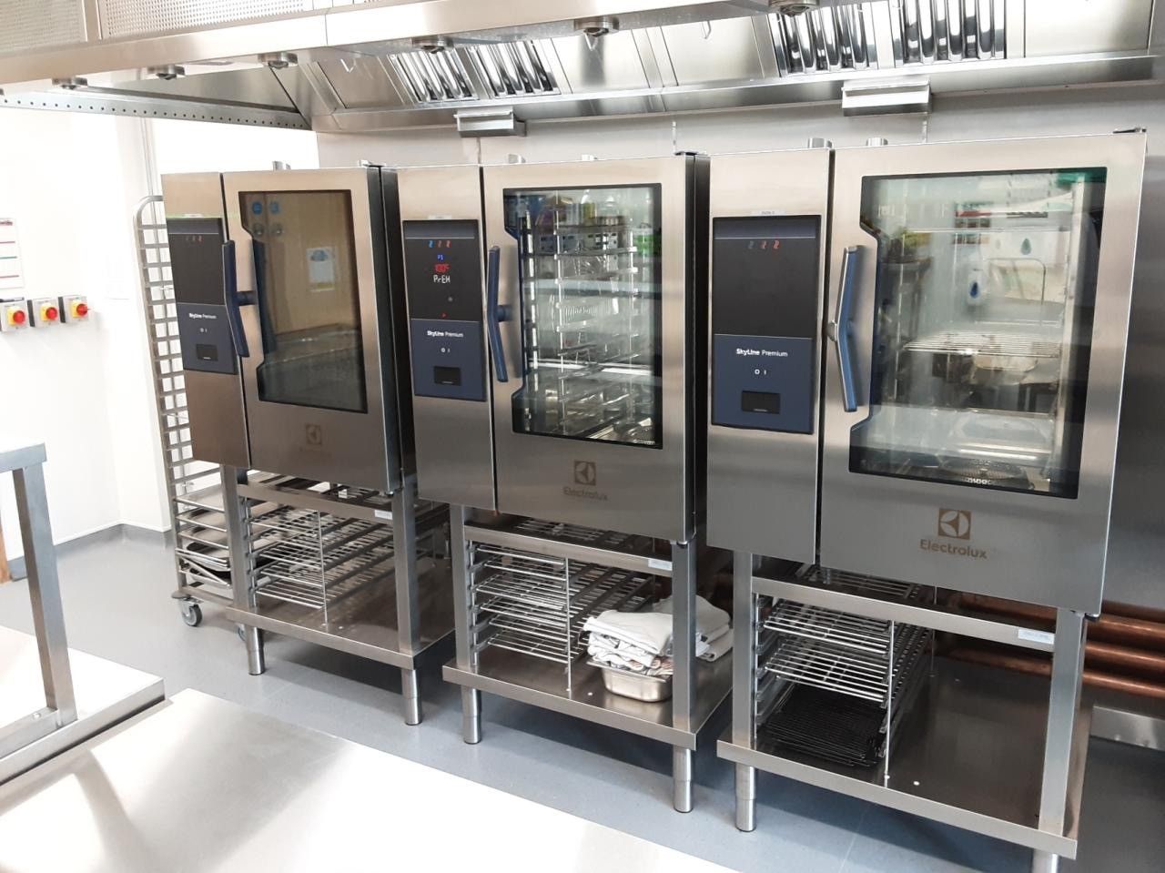 Three newly installed combi ovens on stands in a commercial kitchen